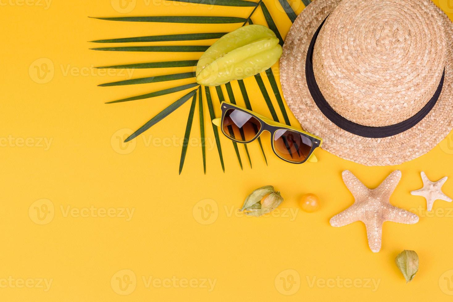 Fruchtkarambolen, Strandzubehör und Blätter einer tropischen Pflanze auf farbigem Papier foto