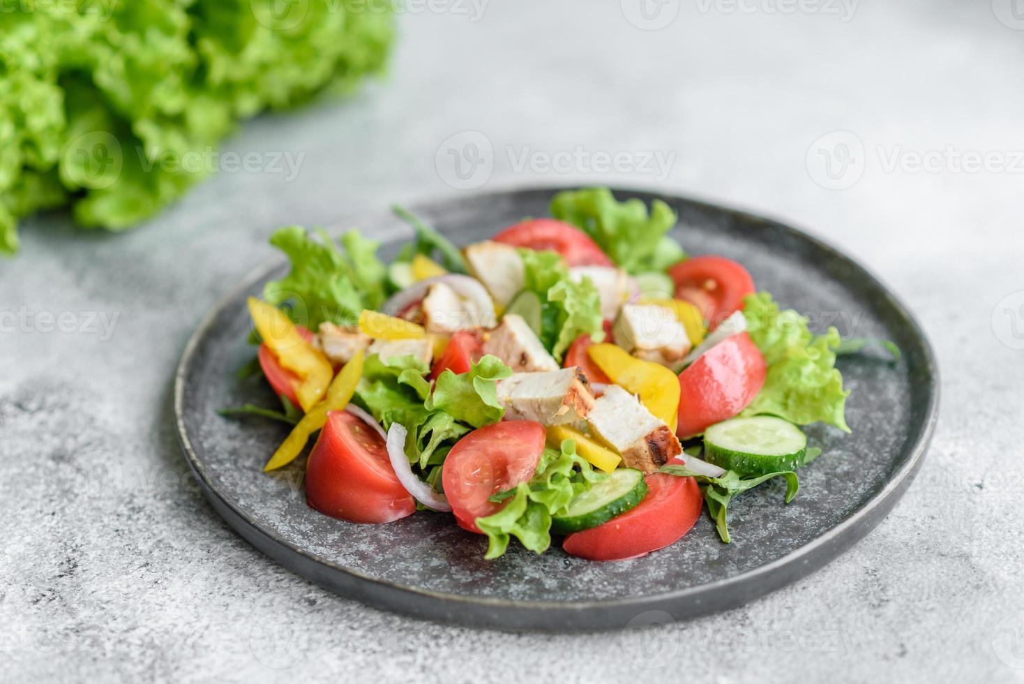 frischer leckerer Salat mit Hühnchen, Tomaten, Gurken, Zwiebeln und Gemüse mit Olivenöl foto