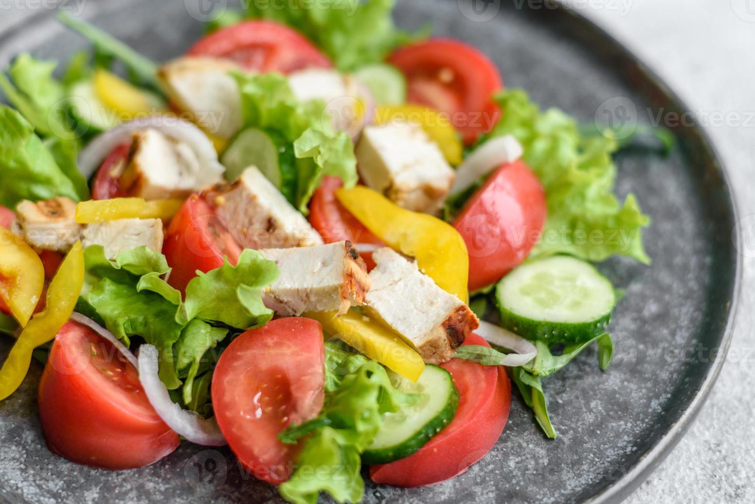 frischer leckerer Salat mit Hühnchen, Tomaten, Gurken, Zwiebeln und Gemüse mit Olivenöl foto