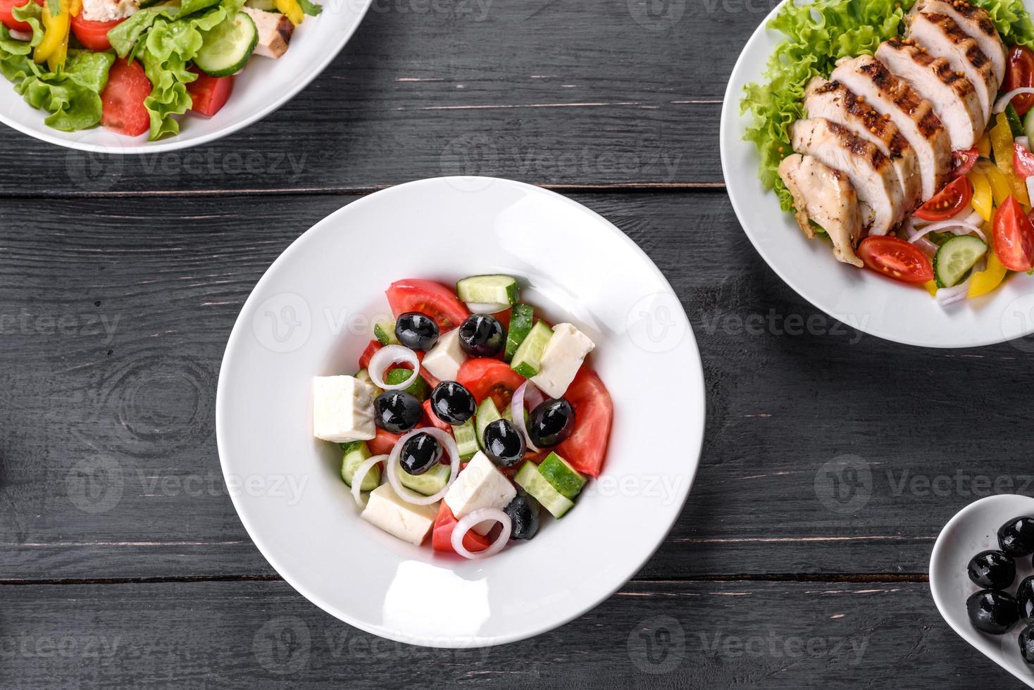 frischer leckerer griechischer Salat mit Tomaten, Gurken, Zwiebeln und Oliven mit Olivenöl foto