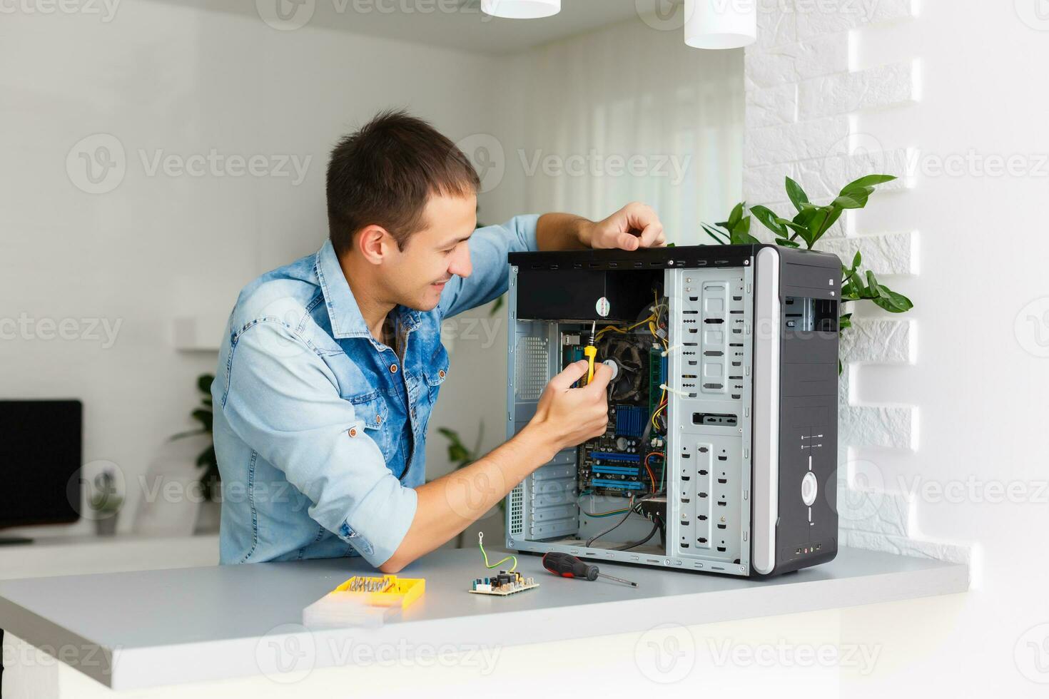 jung Techniker Arbeiten auf gebrochen Computer im seine Büro foto
