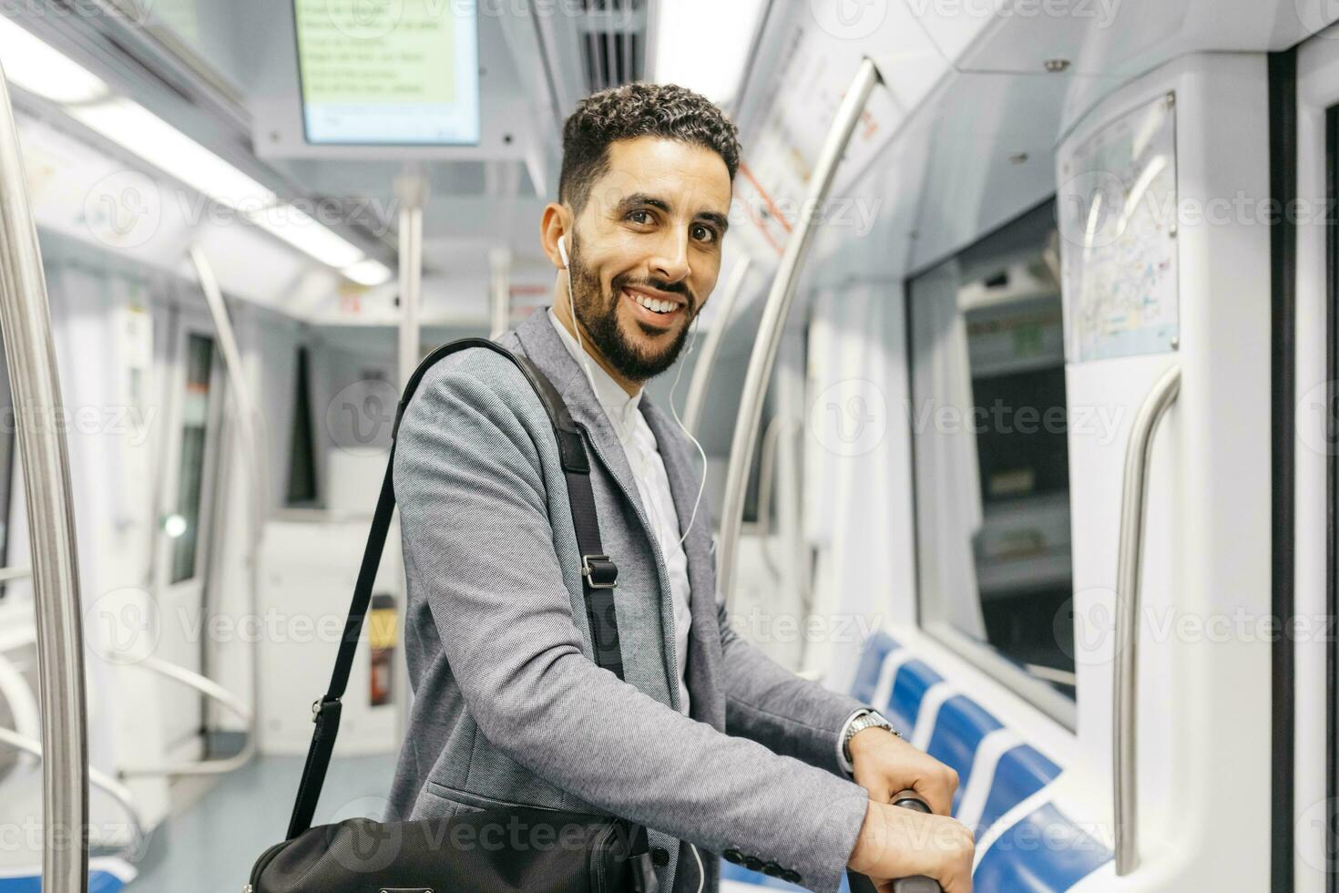 Porträt von lächelnd jung Geschäftsmann mit Kopfhörer auf das U-Bahn foto