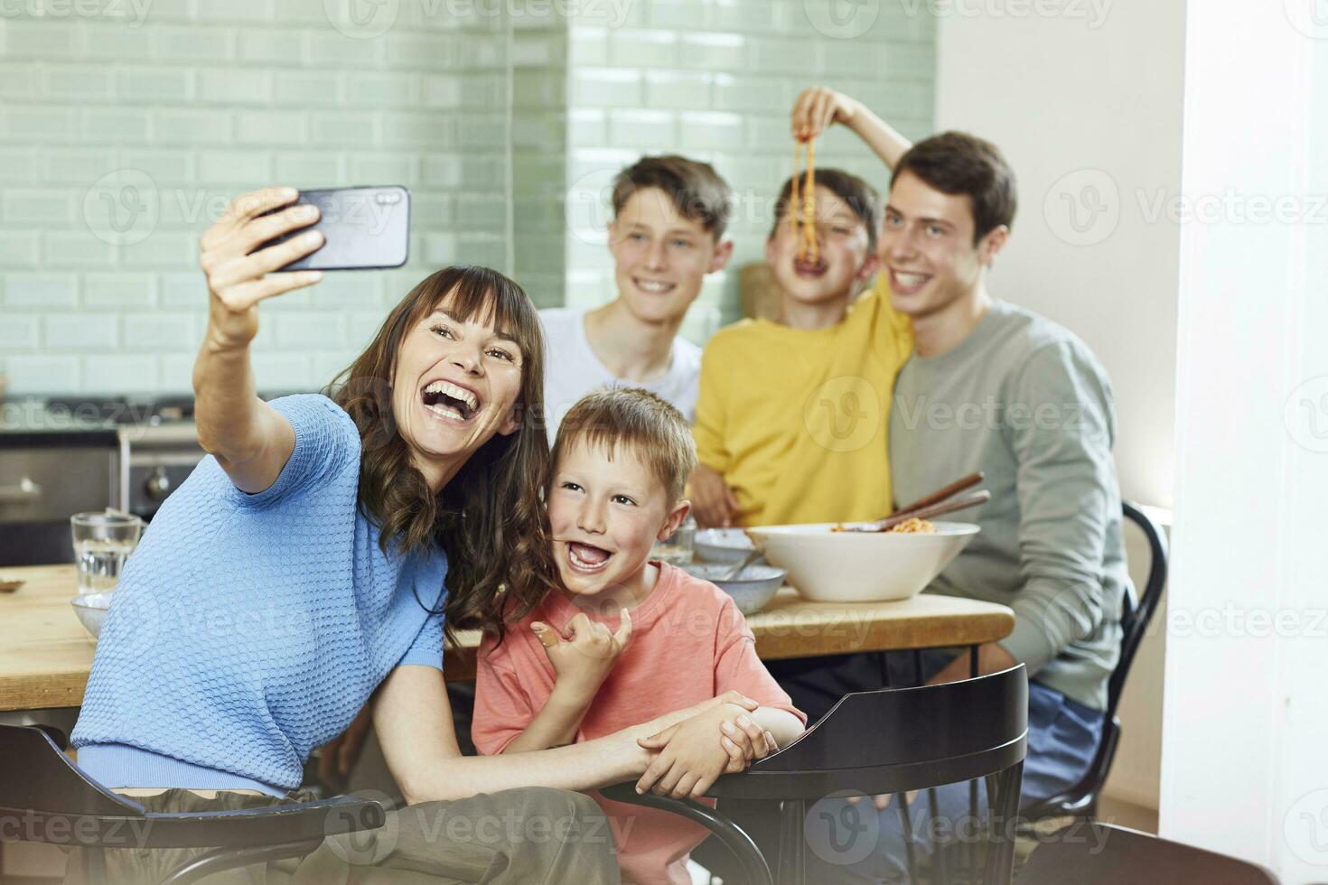 Mutter und ihr vier Söhne nehmen Smartphone Selfies beim Mittagessen foto