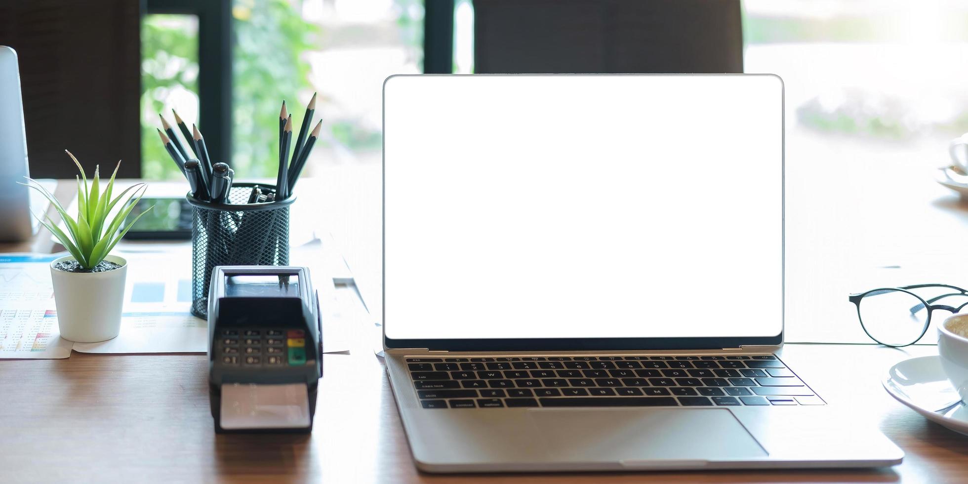 Laptop mit leerem Bildschirm und edc-Maschine auf einem Tisch foto