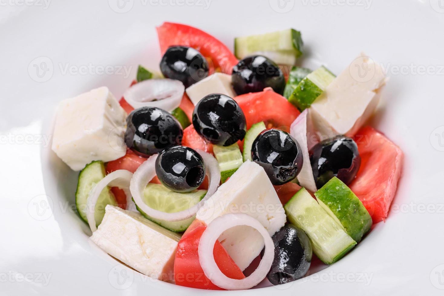 frischer leckerer griechischer Salat mit Tomaten, Gurken, Zwiebeln und Oliven mit Olivenöl foto