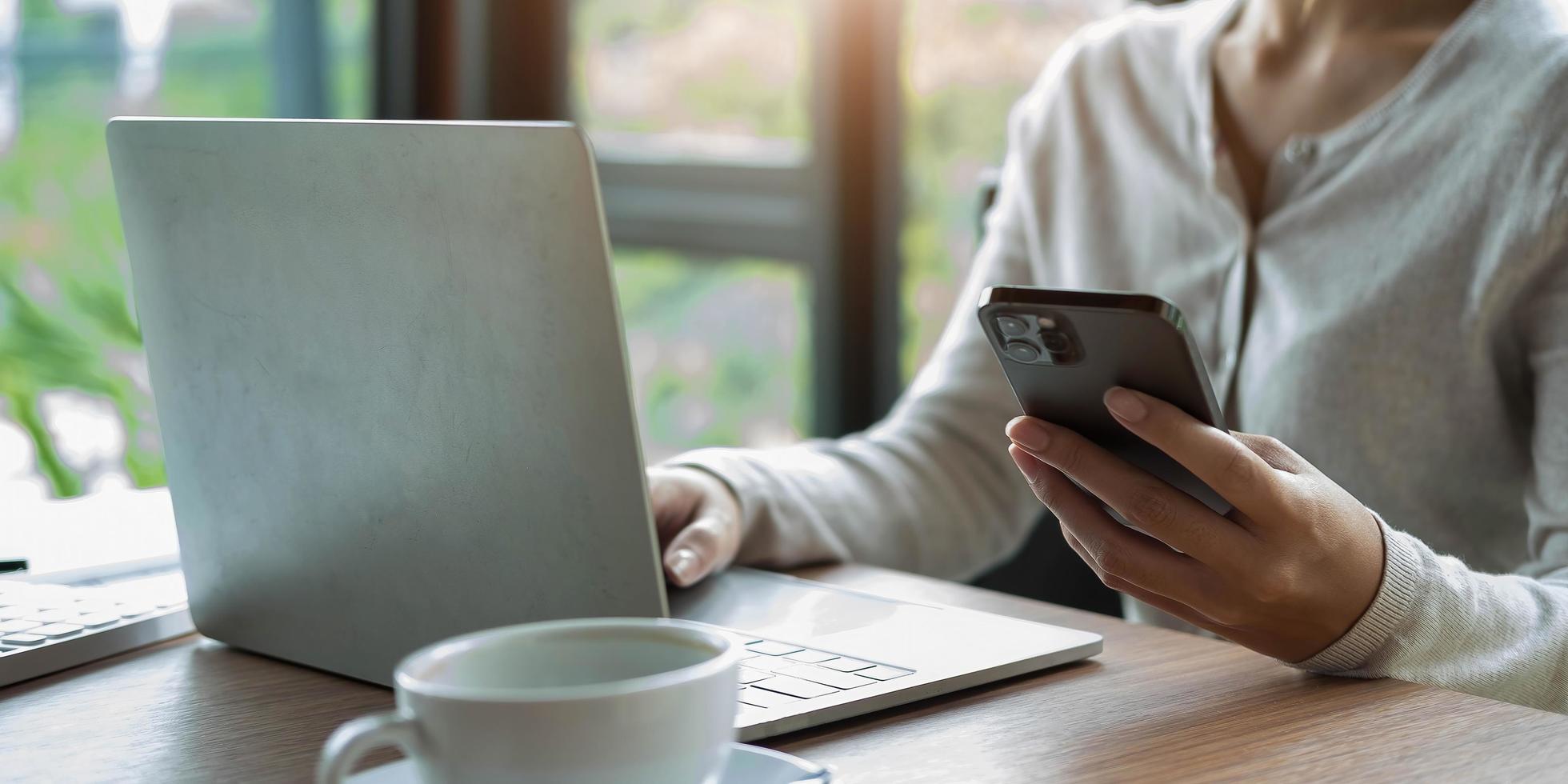 Frau mit Laptop und Handy im Büro foto