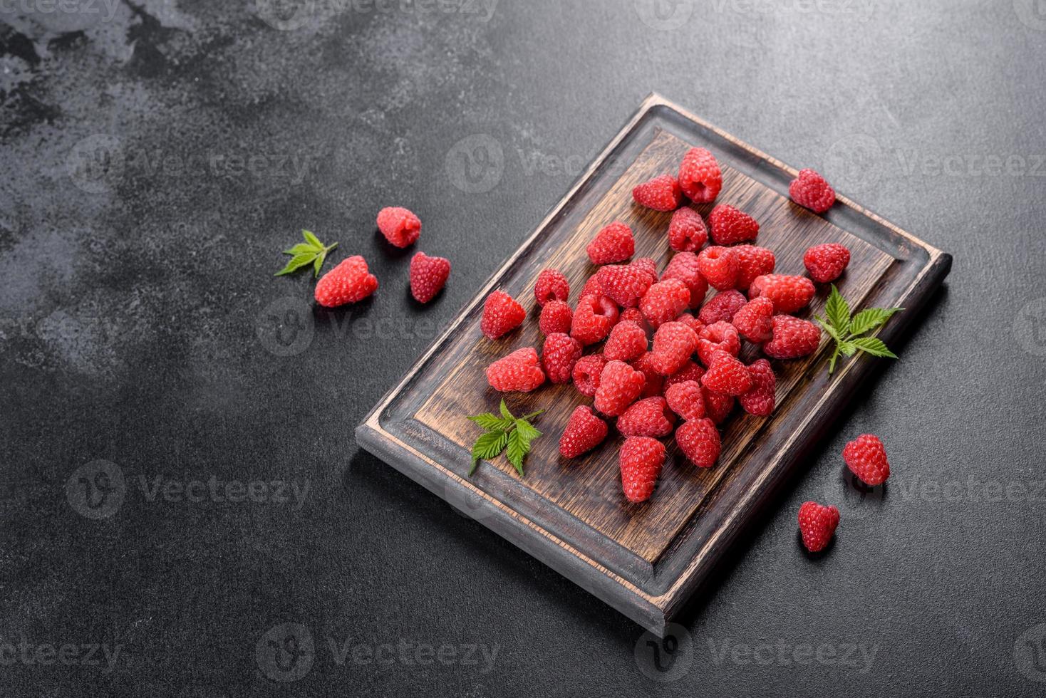 leckere frische saftige rote Himbeeren auf einem dunklen Tisch foto