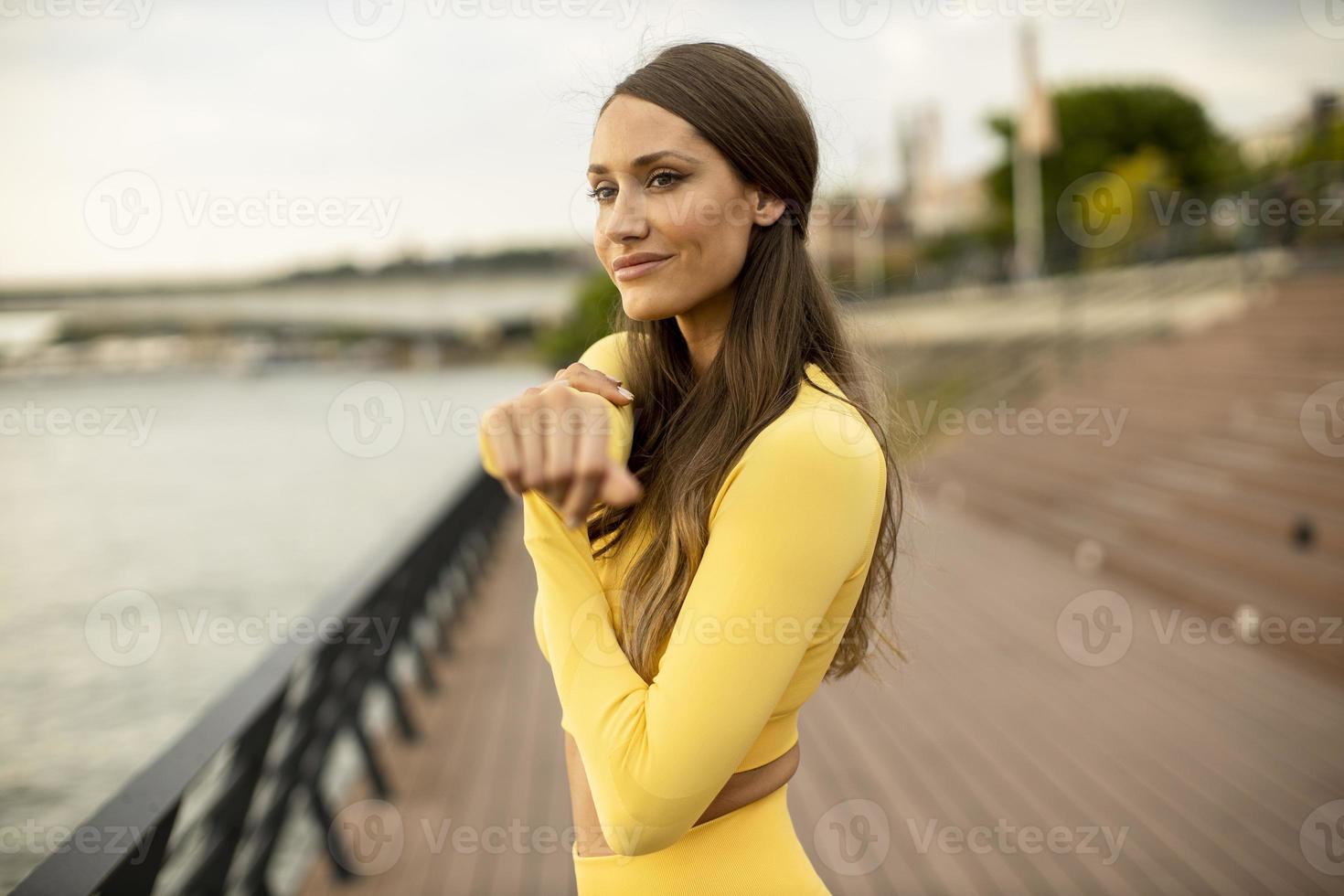 junge Frau streckt sich am Flussufer foto