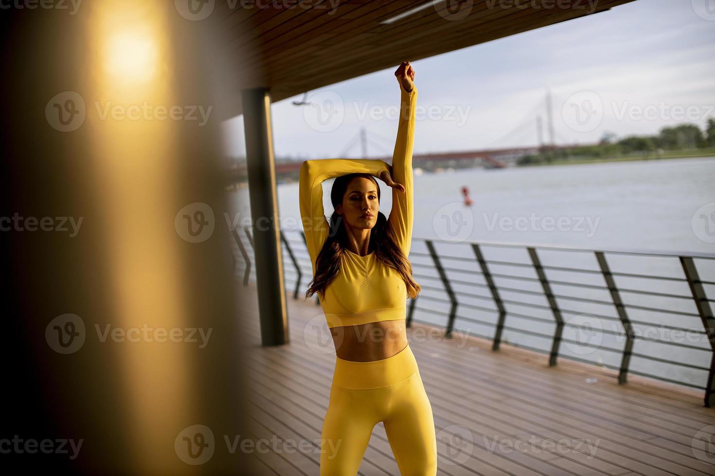 junge Frau streckt sich am Flussufer foto