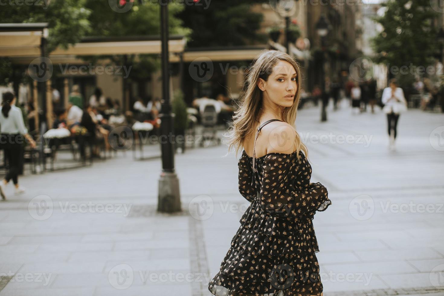 junge brünette Frau mit langen Haaren, die auf die Straße geht foto