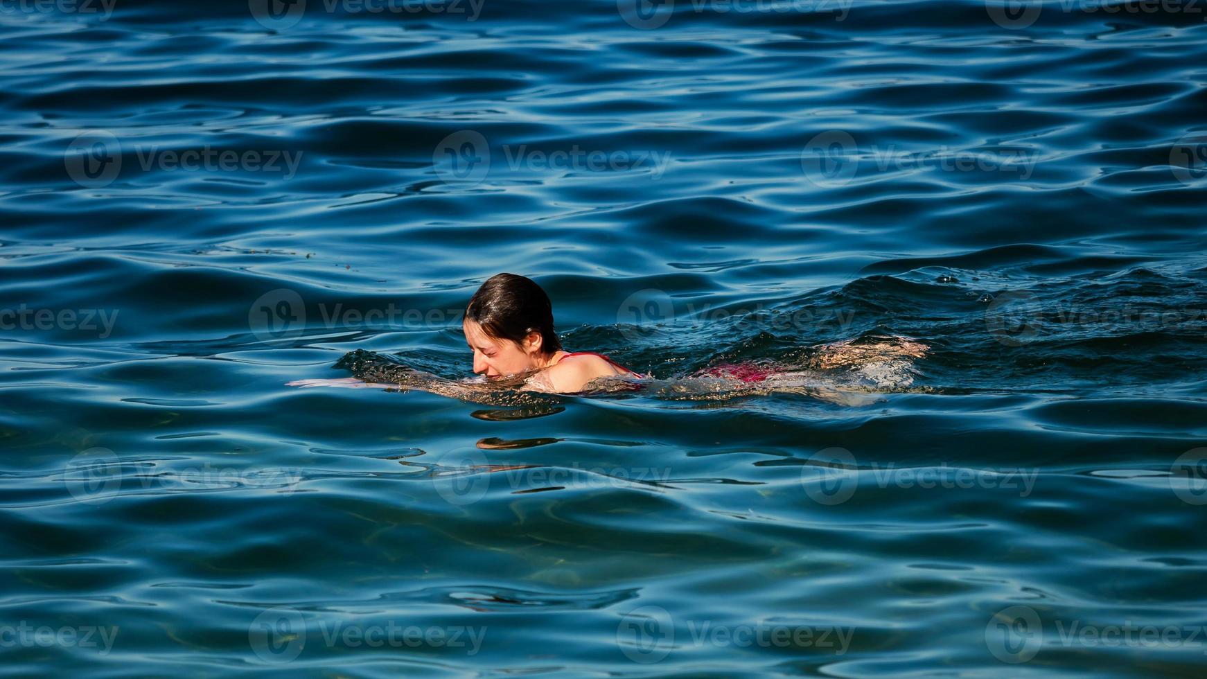 Ein junges Mädchen schwimmt im kristallklaren Wasser eines Bergsees. foto