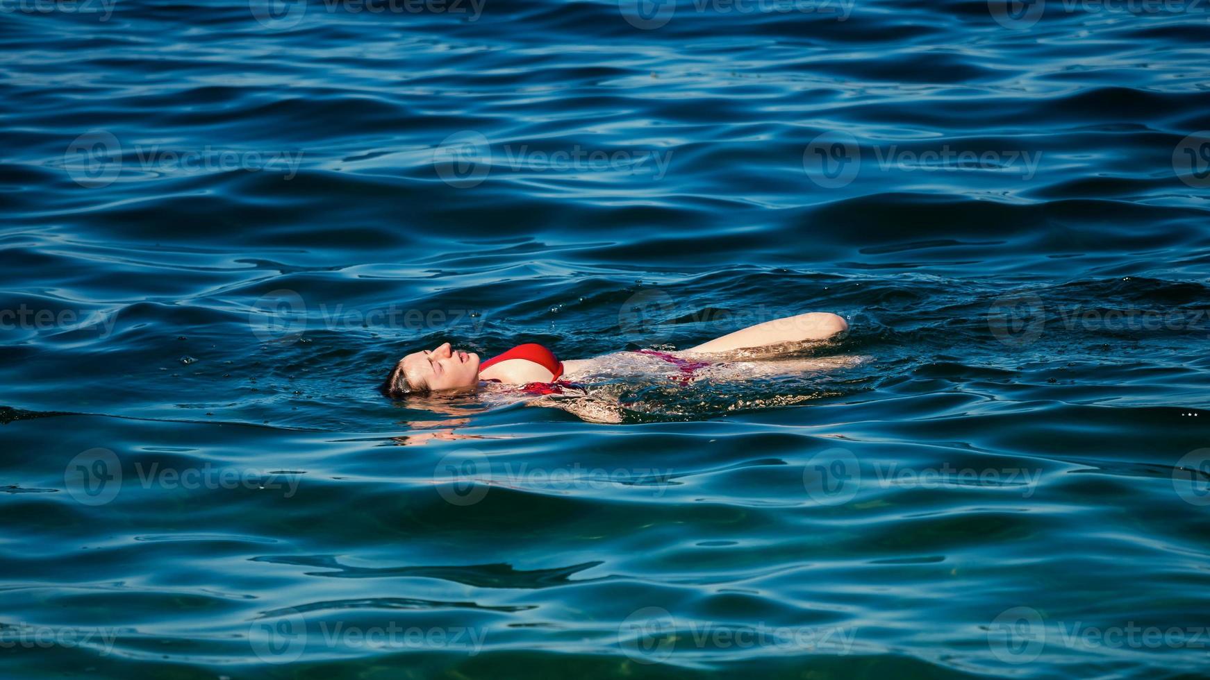 Ein junges Mädchen schwimmt im kristallklaren Wasser eines Bergsees. foto