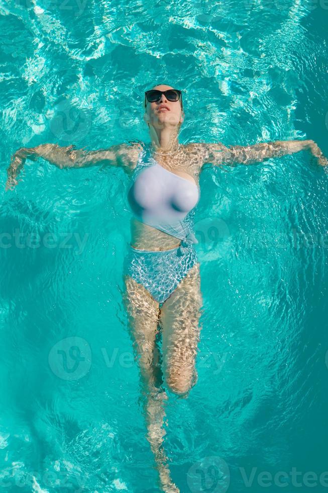 junges schönes sexy Mädchen, das es genießt, im privaten Pool zu schwimmen und sich in der Sonne zu entspannen? foto