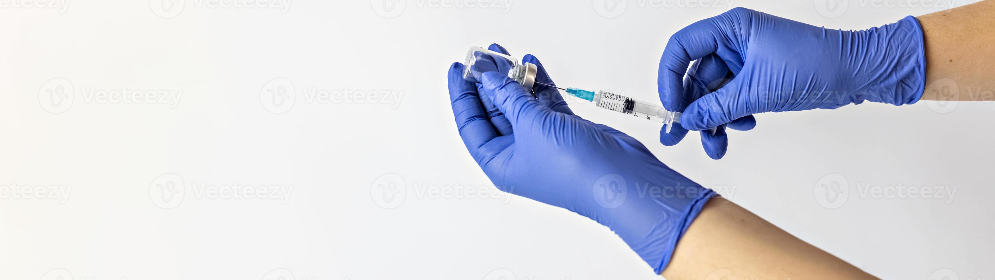 Ein medizinischer Mitarbeiter in medizinischen Handschuhen zieht eine Dosis Coronavirus-Impfstoff in eine Spritze. das Konzept der Impfung, Immunisierung, Prävention von Menschen von Covid-19 foto