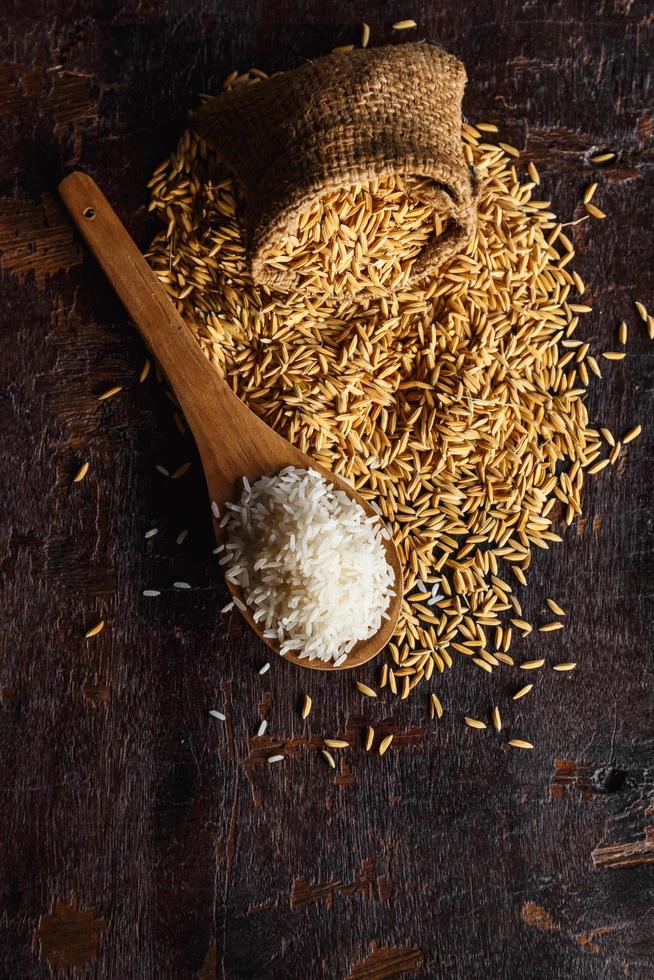 roher gedämpfter Reis und Paddy-Reis auf Holzuntergrund foto