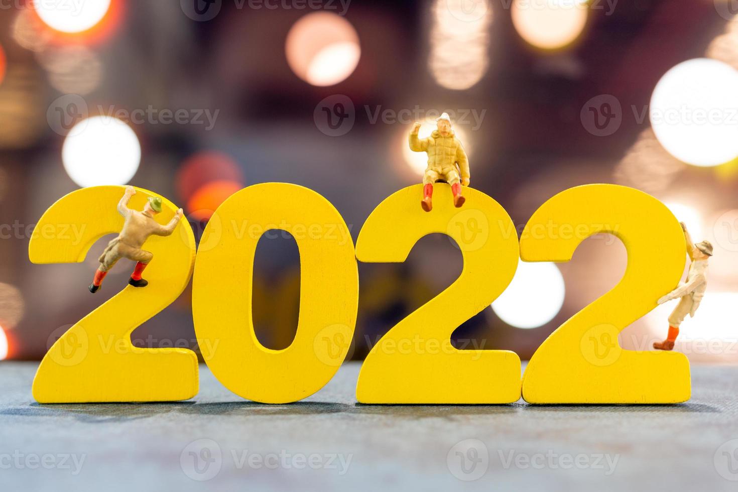 Miniaturmenschen klettern auf Holz mit der Nummer 2022 foto