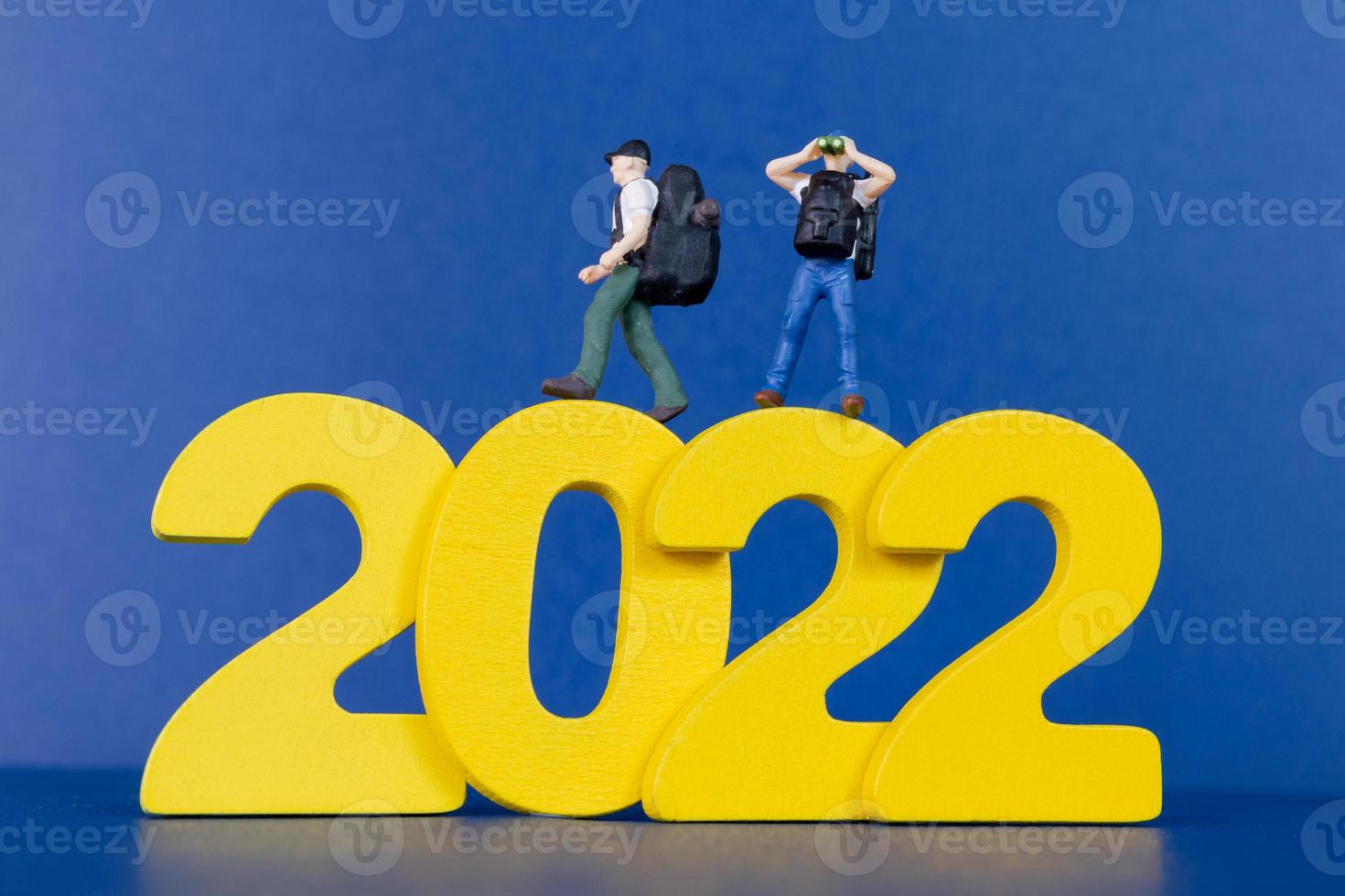 Miniatur-Menschen-Backpacker, der auf Holznummer 2022 steht foto