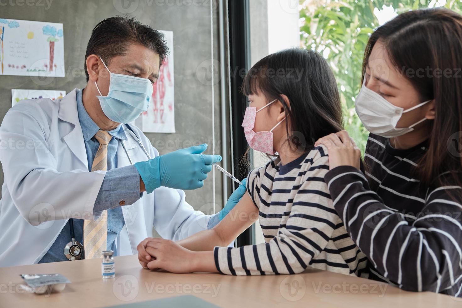 männlicher Arzt impfen asiatisches Mädchen in der Kinderklinik. foto