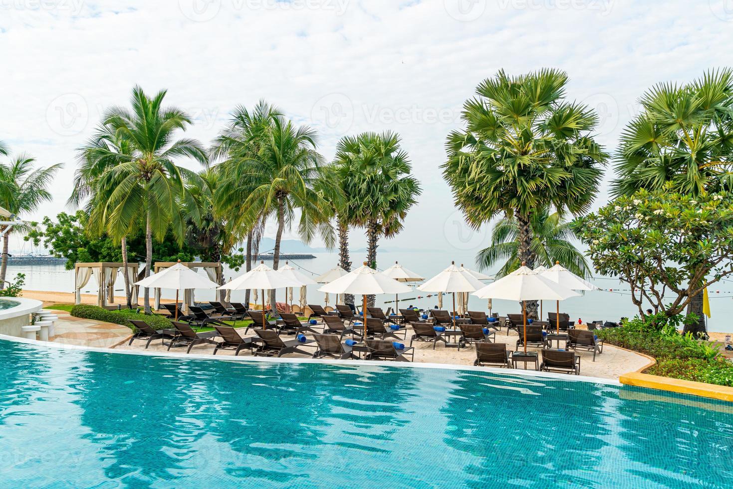 leerer Strandkorb mit Sonnenschirm um den Pool herum foto