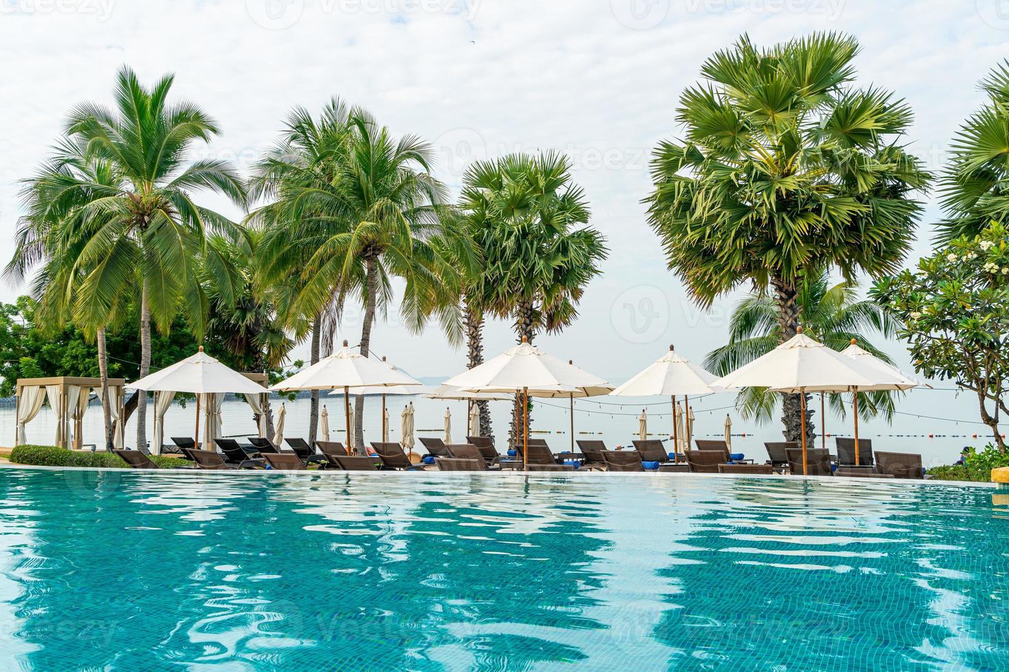 leerer Strandkorb mit Sonnenschirm um den Pool herum foto