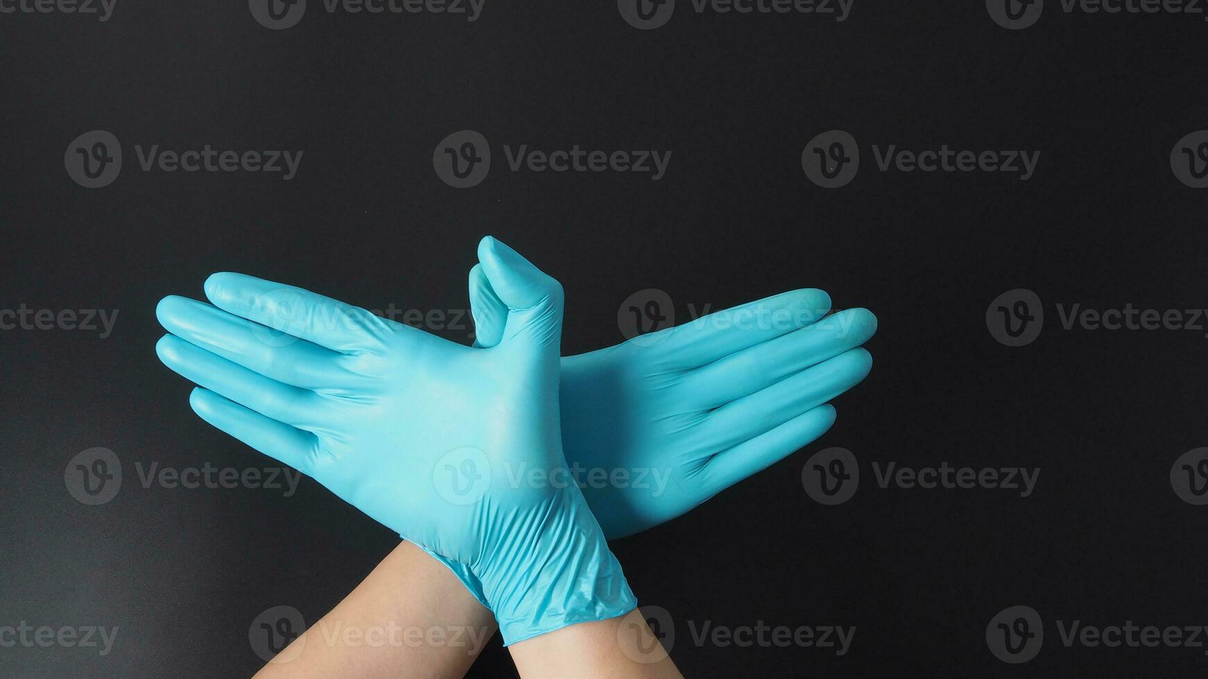 zwei Hand tragen Blau Latex Handschuhe tun Hände mögen Flügel auf schwarz Hintergrund. foto