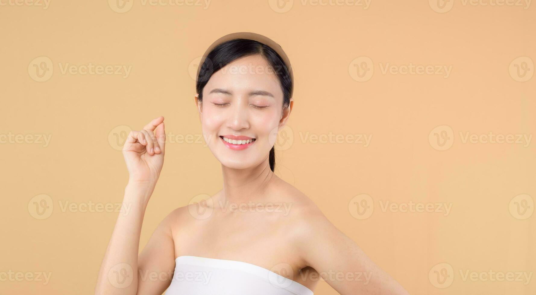Schönheit asiatisch jung Frau Modell- mit frisch glühend hydratisiert Gesichts- Haut. Mädchen Person mit natürlich bilden und gesund Haut Porträt isoliert auf Beige Studio Hintergrund. Spa Behandlung, Haut Pflege Konzept. foto