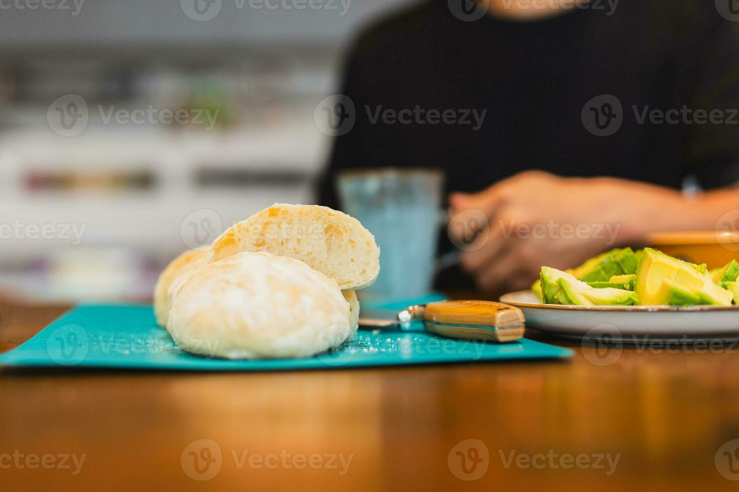 frisch geschnitten gebacken Brot auf Hacken Tafel mit Mann halten Kaffee Tasse. foto