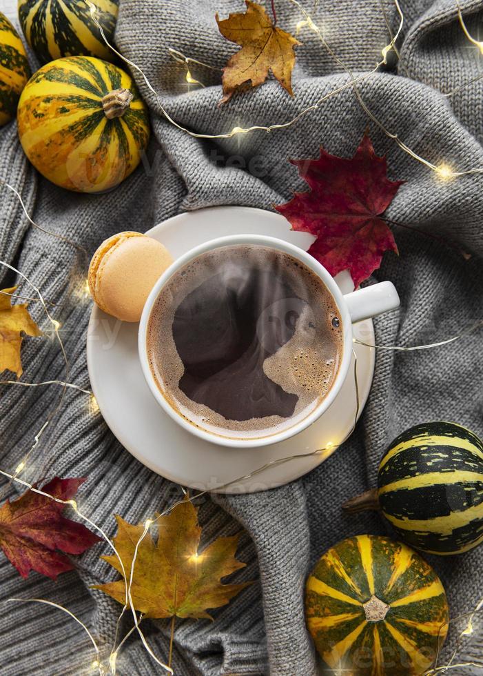 Tasse Kaffee, trockene Blätter und Schal auf einem Tisch foto