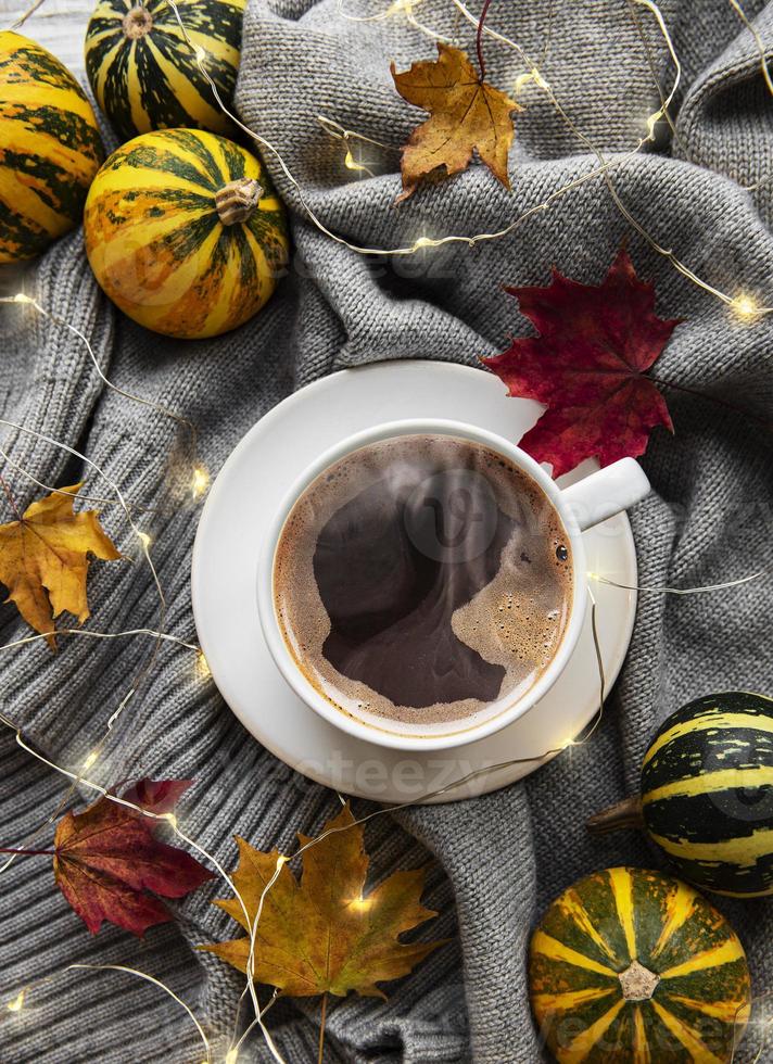 Tasse Kaffee, trockene Blätter und Schal auf einem Tisch foto