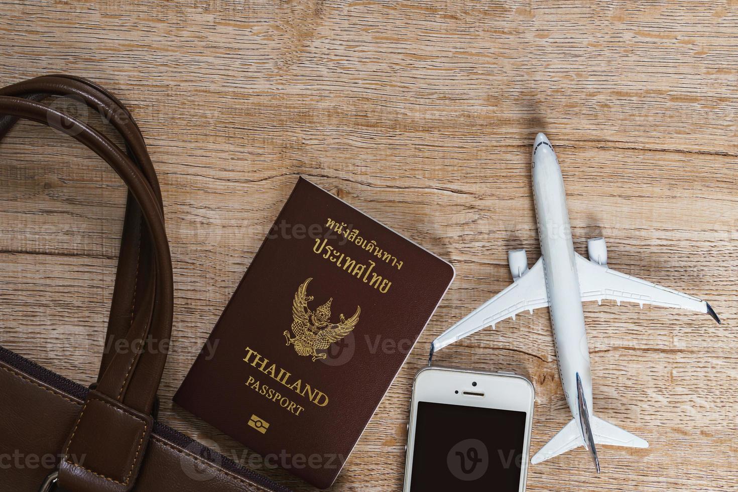 Ledertasche und kleines Flugzeugmodell auf Holzbretthintergrund foto