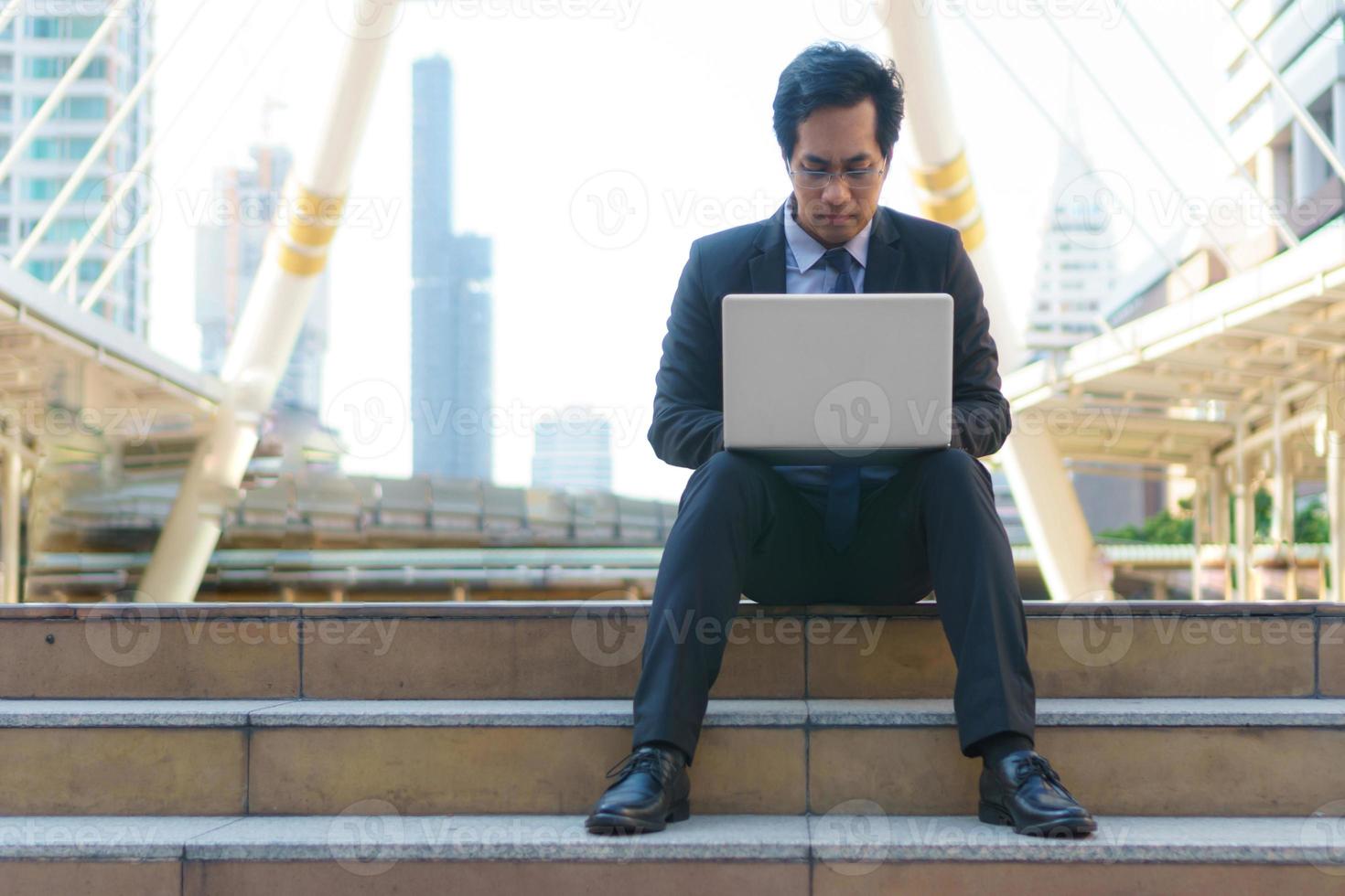 Geschäftsmann sitzt auf den Spuren mit Laptop foto