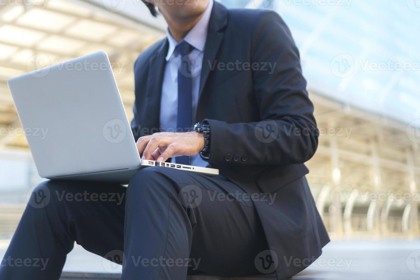 Geschäftsmann sitzt auf den Spuren mit Laptop foto