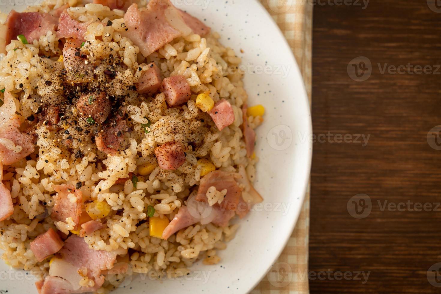 gebratener Reis mit Speck, Schinken und schwarzer Paprika auf weißem Teller foto