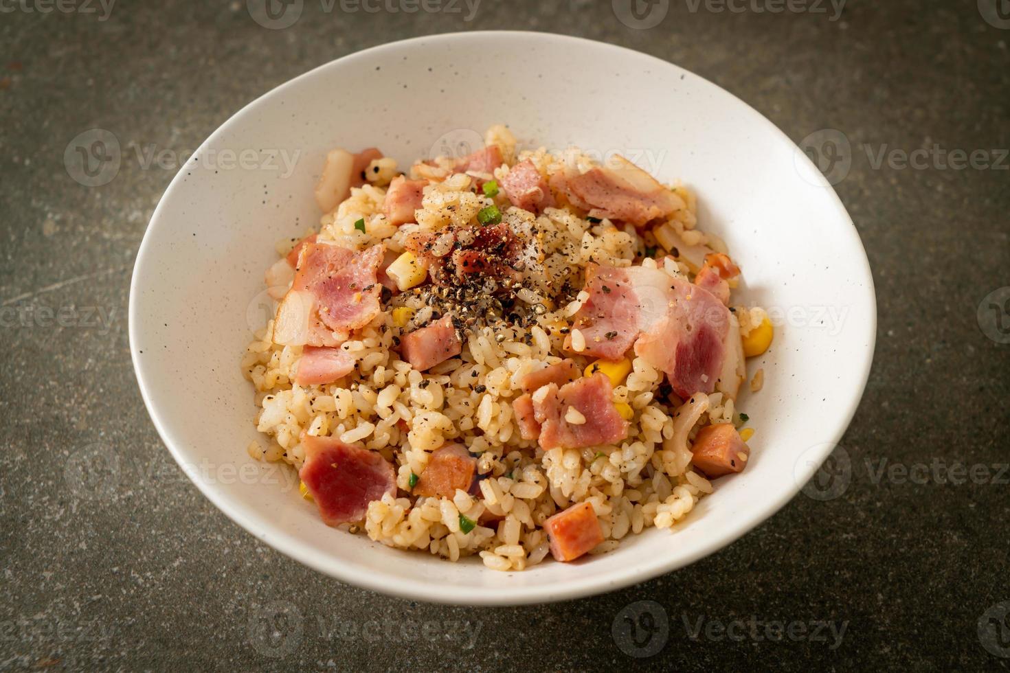 gebratener Reis mit Speck, Schinken und schwarzer Paprika auf weißem Teller foto