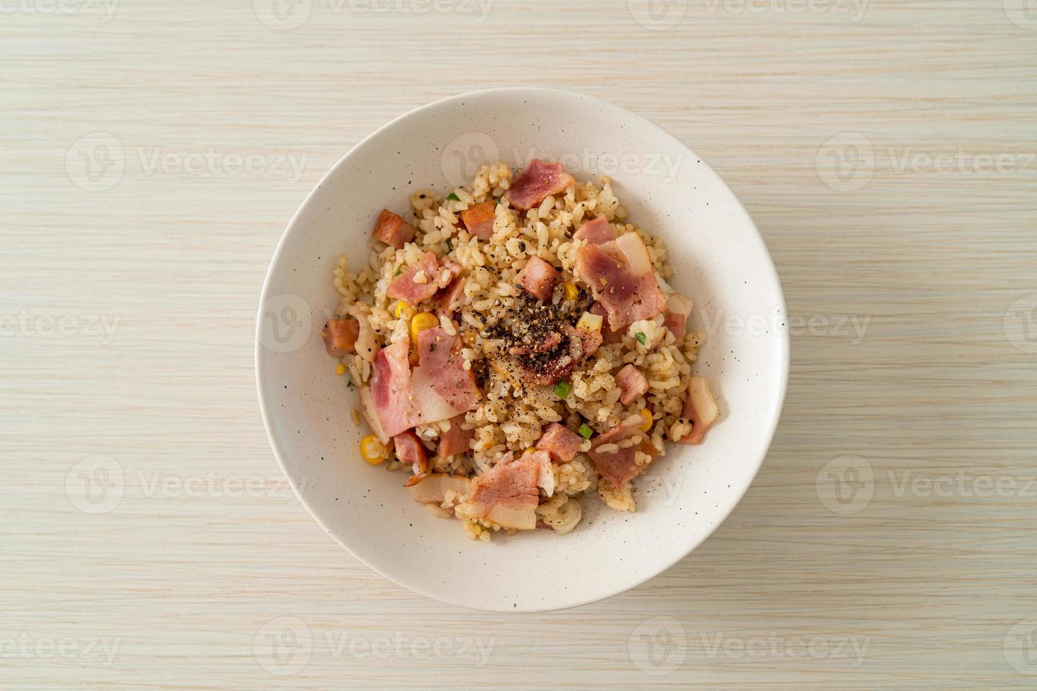 gebratener Reis mit Speck, Schinken und schwarzer Paprika auf weißem Teller foto