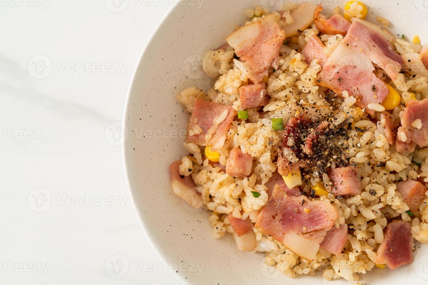 gebratener Reis mit Speck, Schinken und schwarzer Paprika auf weißem Teller foto