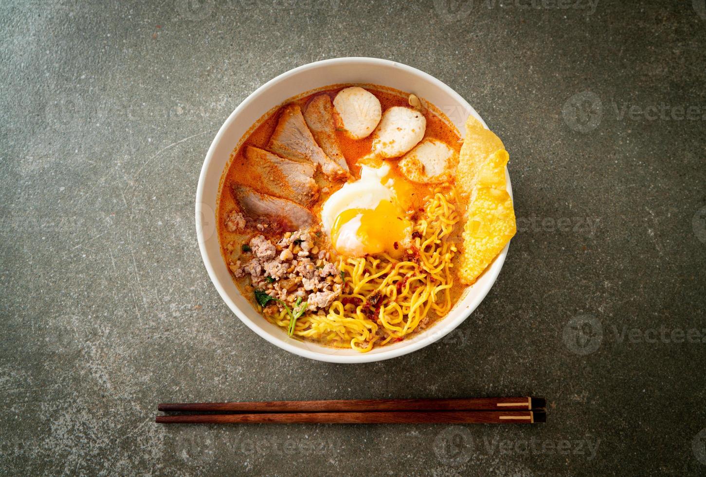 Eiernudeln mit Schweinefleisch und Frikadellen in pikanter Suppe oder Tom Yum Nudeln nach asiatischer Art foto