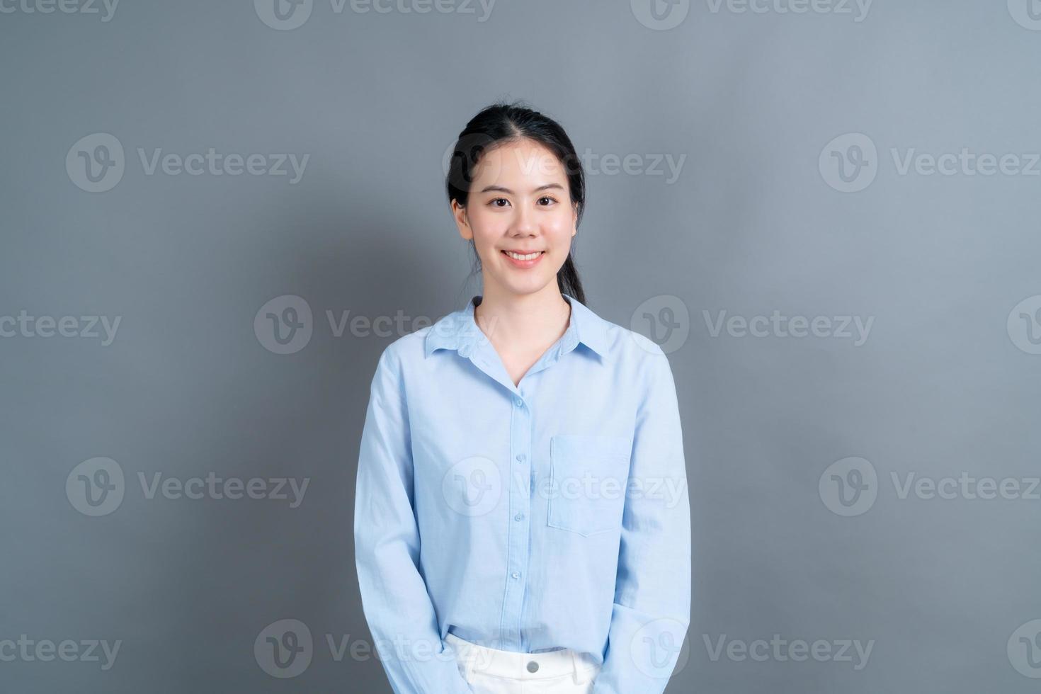 glückliche asiatische Frau mit glücklichem Gesicht im blauen Hemd auf grauem Hintergrund gray foto