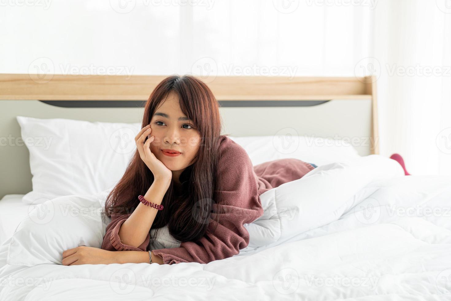 schöne asiatische frau, die morgens auf dem bett liegt foto