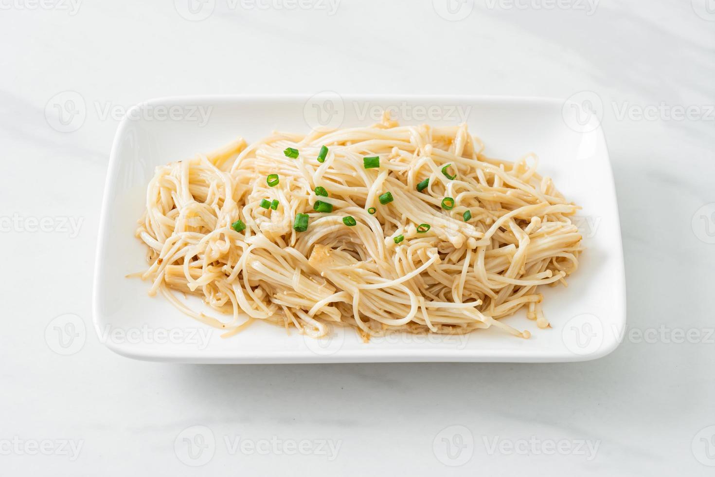 gebratener goldener Nadelpilz mit Butter auf weißem Teller foto