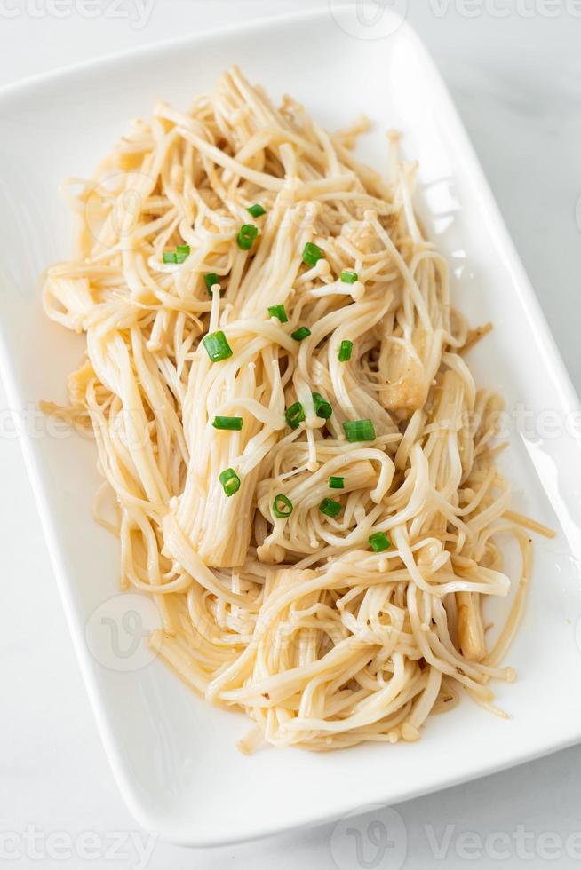 gebratener goldener Nadelpilz mit Butter auf weißem Teller foto