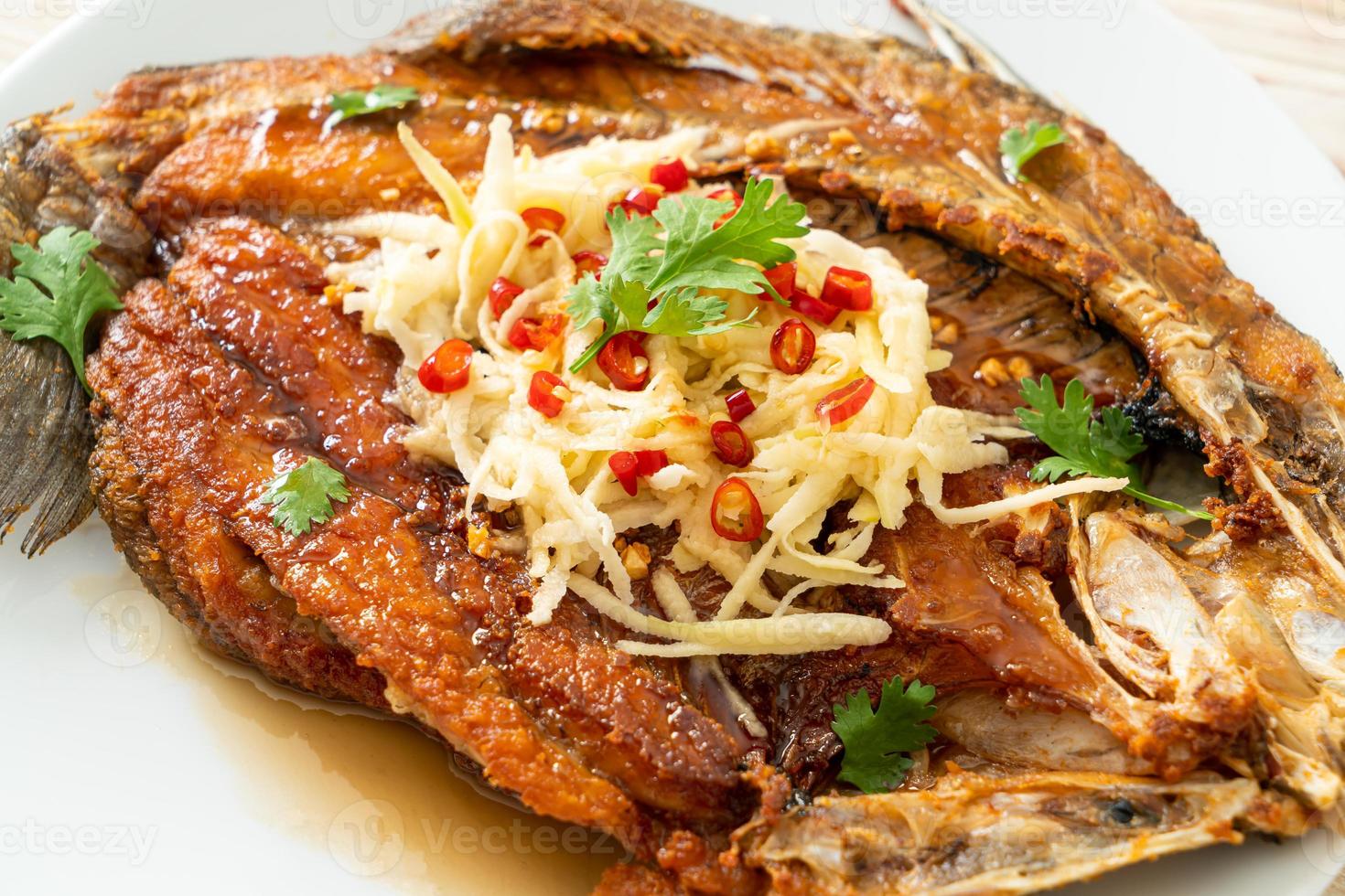 gebratener Wolfsbarsch mit Fischsauce und würzigem Salat foto