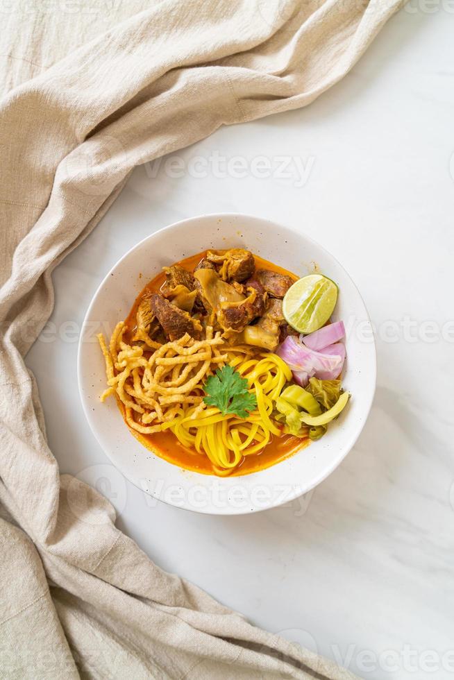 Nordthailändische Nudel-Curry-Suppe mit geschmortem Schweinefleisch foto