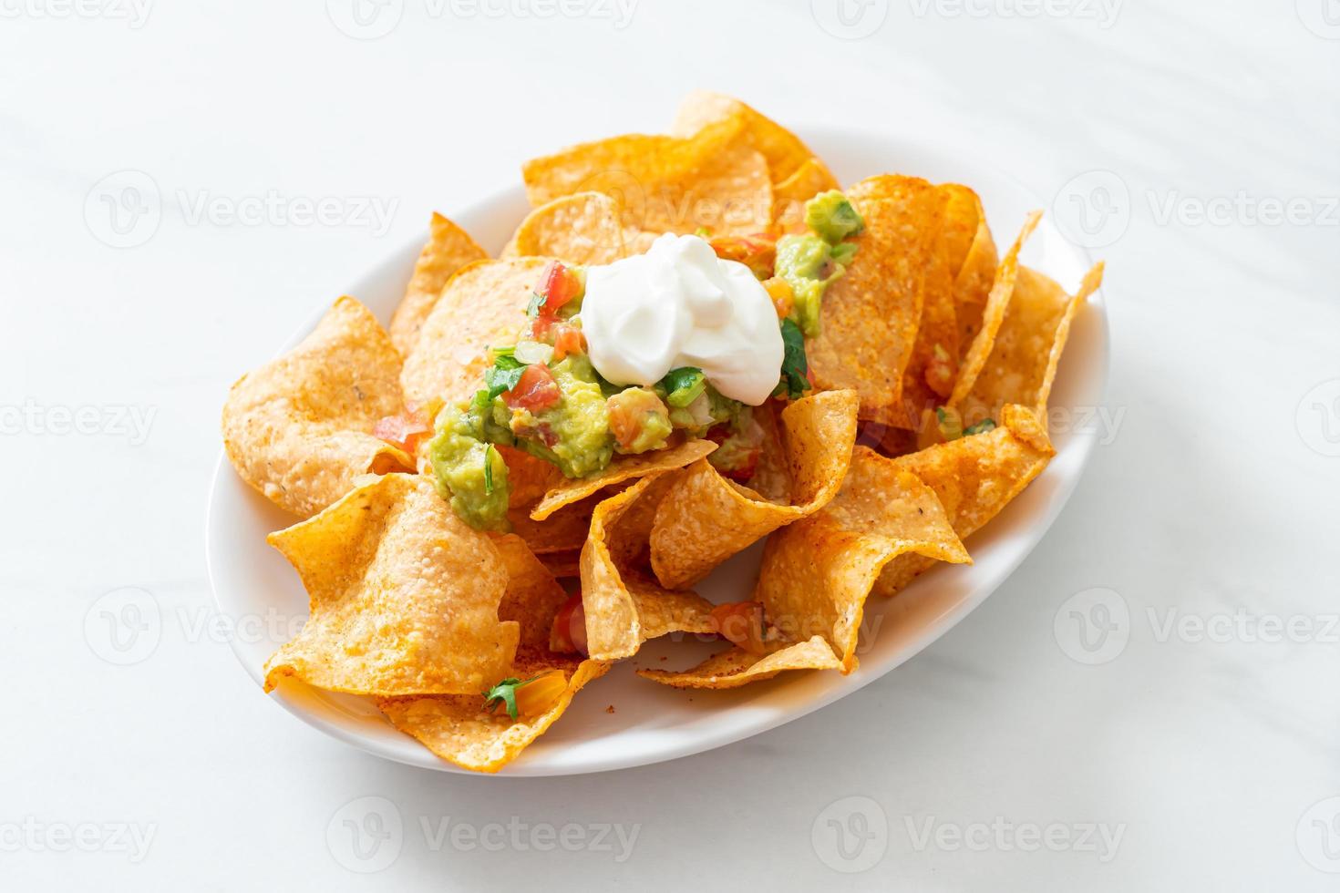 mexikanische Nachos-Tortilla-Chips mit Jalapeno, Guacamole, Tomatensalsa und Dip foto