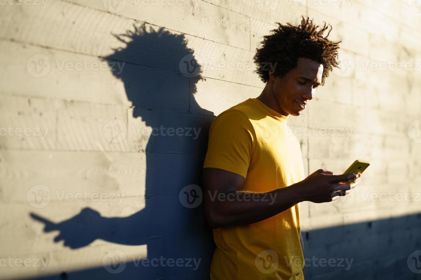 schwarzer Mann konsultiert sein Smartphone, während er sich von seinem Training ausruht. foto
