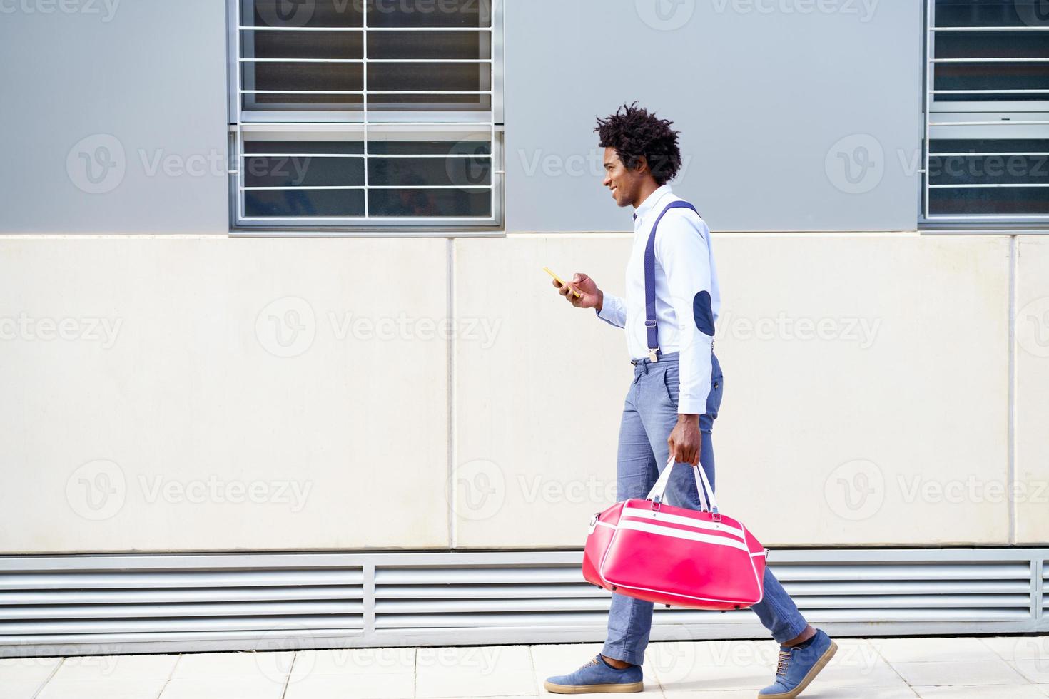 schwarzer Mann mit Afro-Frisur, der eine Sporttasche trägt foto