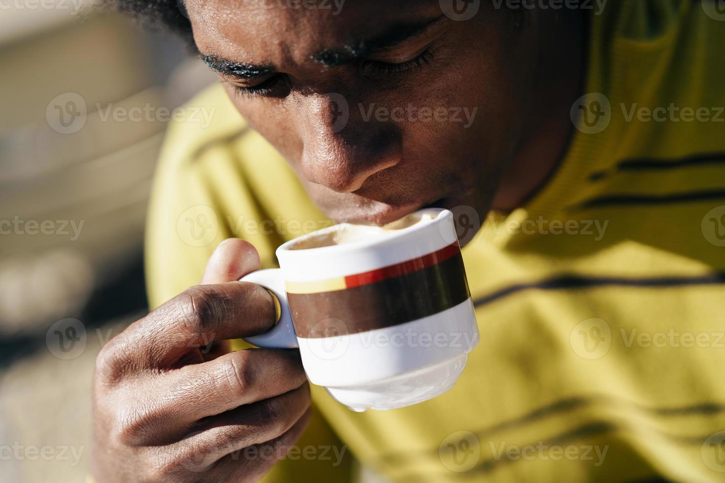 schwarzer Mann genießt Kaffee im Café, während er draußen am Tisch sitzt foto