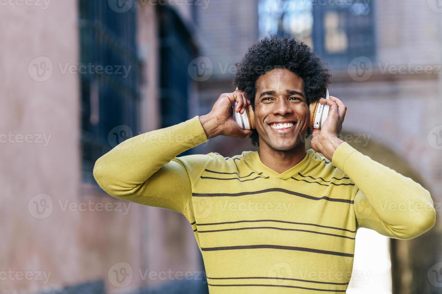 Schwarzer Mann, der mit drahtlosen Kopfhörern Musik hört foto