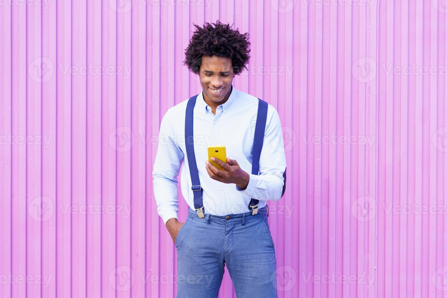 schwarzer Mann mit Afro-Frisur mit Smartphone foto