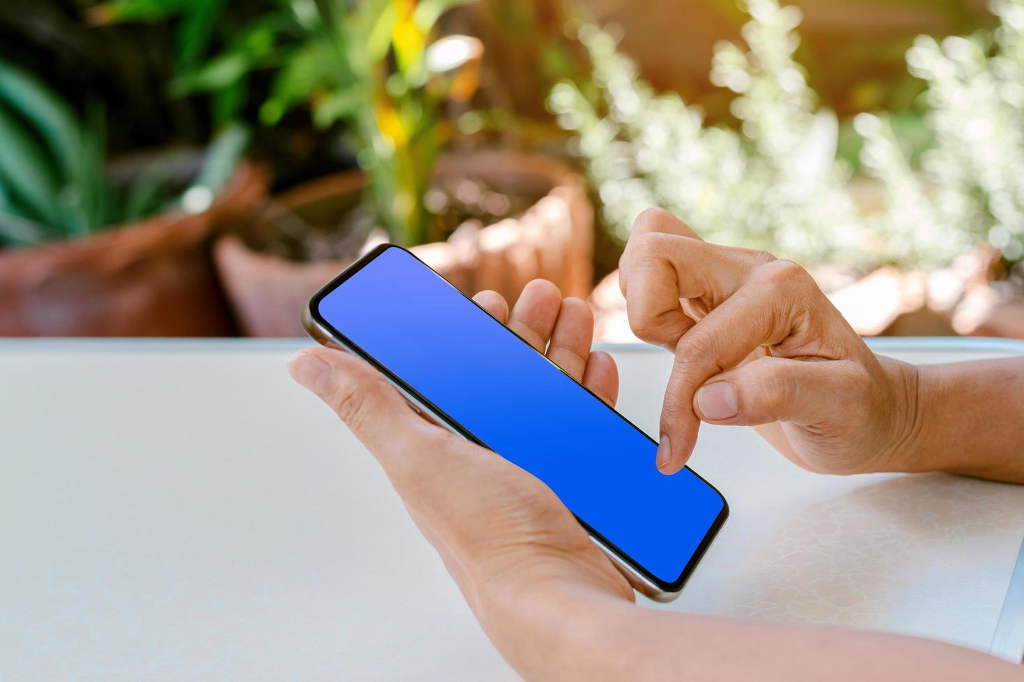 Hand des menschlichen Berührens auf blauem Bildschirm des Smartphones foto